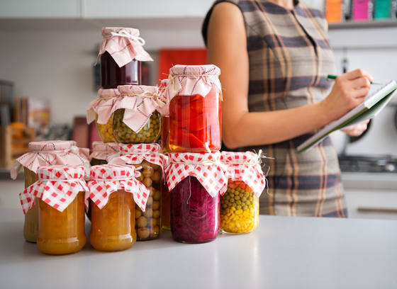woman with checklist and stack of preserved canned foods