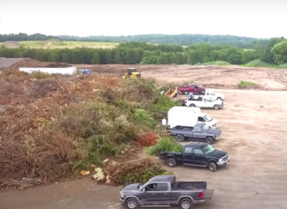 trucks backed into wood waste area unloading brush and branches