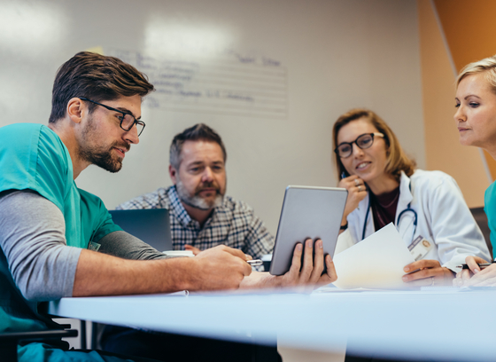 Medical Personnel Reviewing File on a tablet sitting in a meeting room