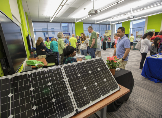 In this color photo at GreenFest 2019, attendees visit vendors in a conference room.