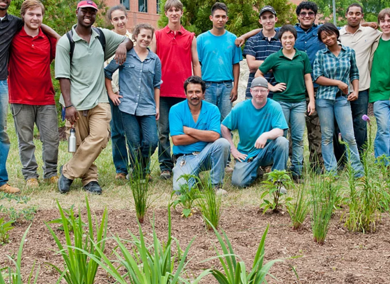 This color photo shows a group of Howard EcoWorks staff stand behind a newly planted landscape.