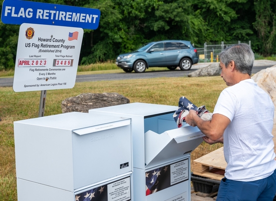 man placing flag in metal box for flag retirement