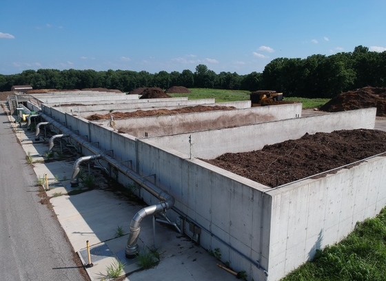 composting facility bunkers filled with compost and metal piping along the concrete wall