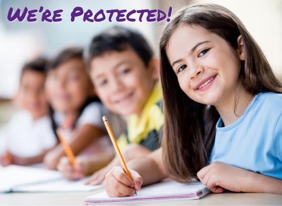 Line of school children at desks with pencils in hand the girl to the right is in clear focus the others are blurred. Text: We're Protected